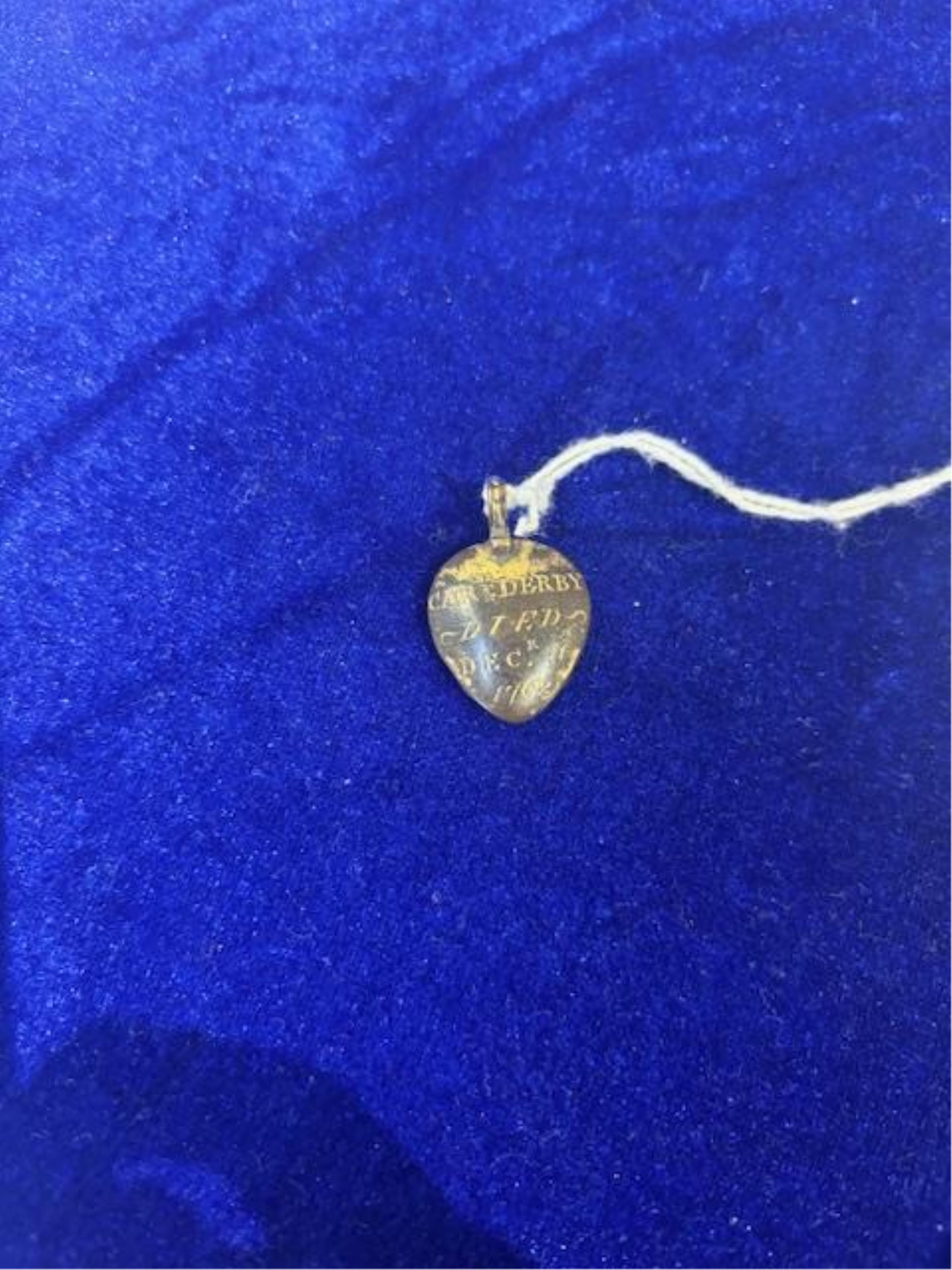 An 18th century gilt metal heart shaped mourning pendant, with engraved inscription, 'CARna DERBY DIED DEC 11th, 1762' and plaited hair beneath a glazed panel verso, 27mm.